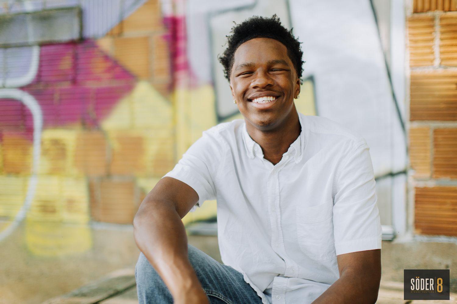 smiling young man with graffiti behind him