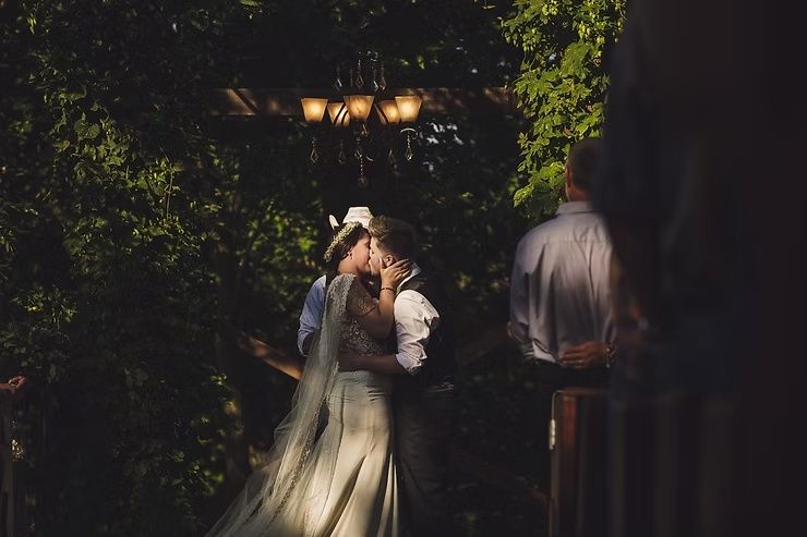 same-sex wedding couple kissing during outdoor wedding ceremony in northern iowa