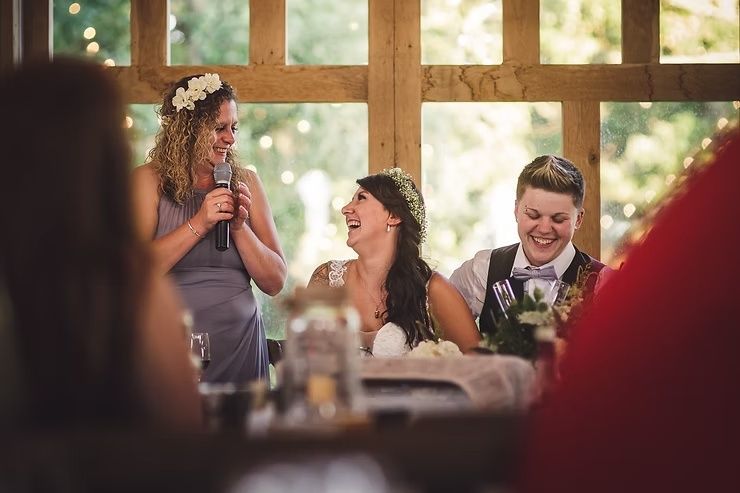 same sex bride and groom laughing during reception speech