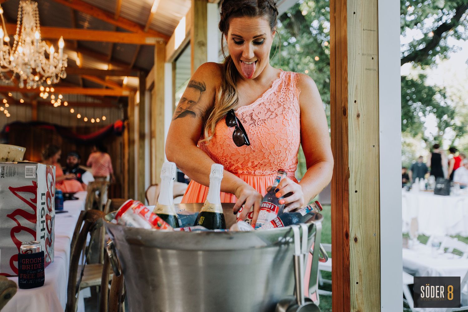 bridesmaid sticking her tongue out while finding a beer in a cooler at diamond oak events in clear lake, iowa