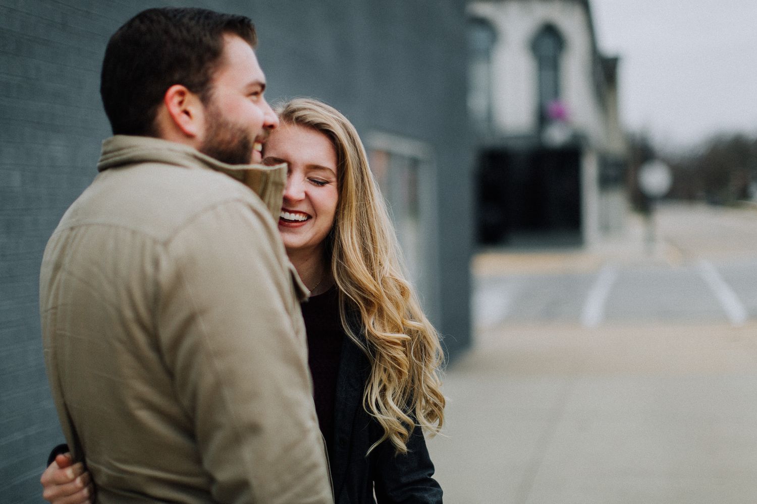 man and woman hugging on charles city, iowa street for engagement photo