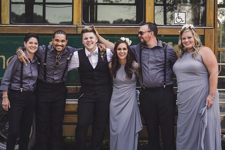 lgbtq groom and best men at iowa barn wedding in front of trolley bus