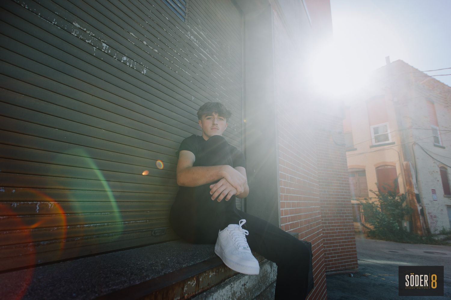 senior portrait of boy on loading dock with sun flare
