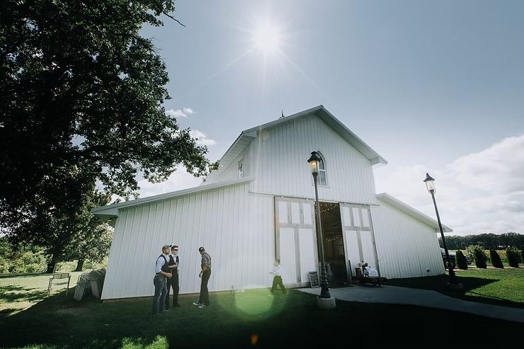 groomsmen standing outside of large barn for iowa wedding