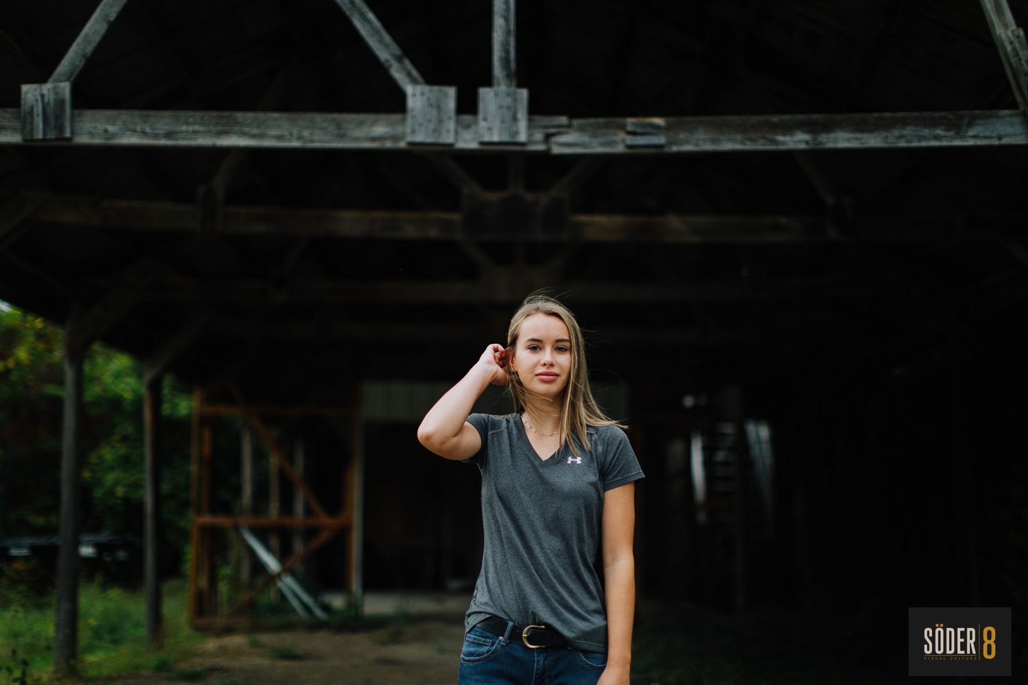 high school senior girl standing in light under barn rafters in rockford, iowa - soder 8