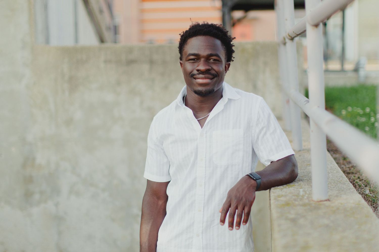 High school senior boy smiling with arm resting on a wall.