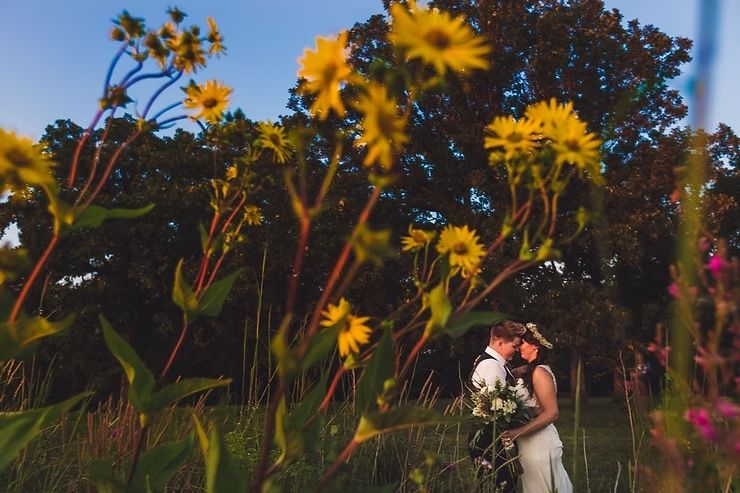 same sex couple on iowa prairie with flowers taller than they are