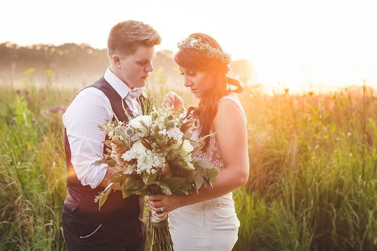 LGBTQ couple at sunset looking at flowers on iowa prairie