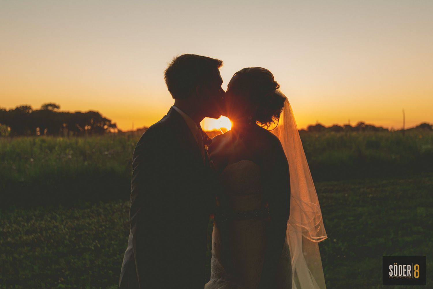 silhouette of bride and groom kissing at sunset