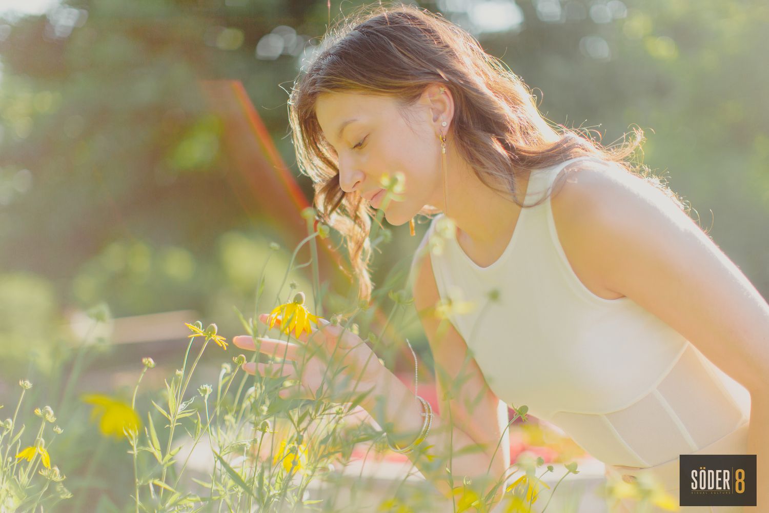 high school senior girl smelling flowers in garden