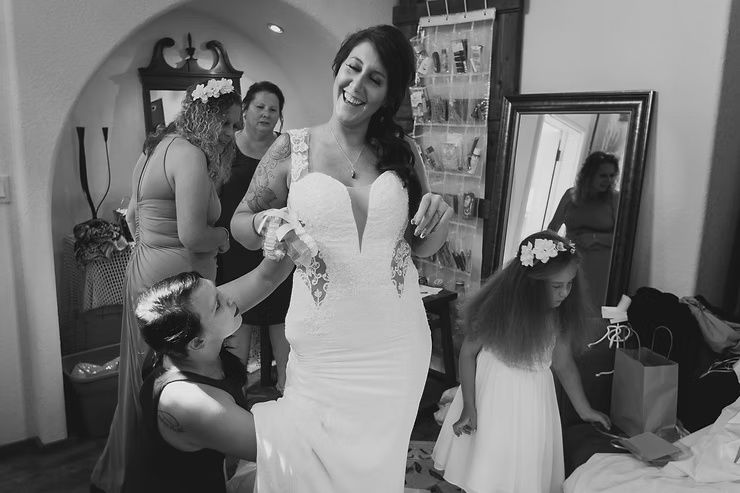 bride laughing while her dress is being pulled up while getting ready for wedding