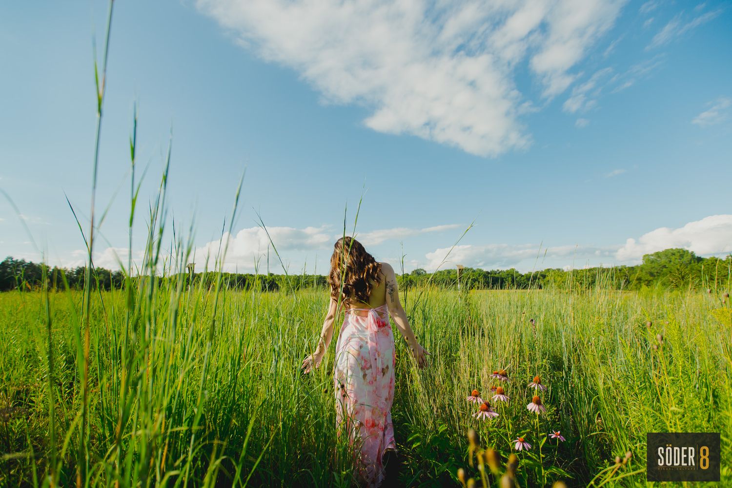 high school girl walking through prairie flowers in dress