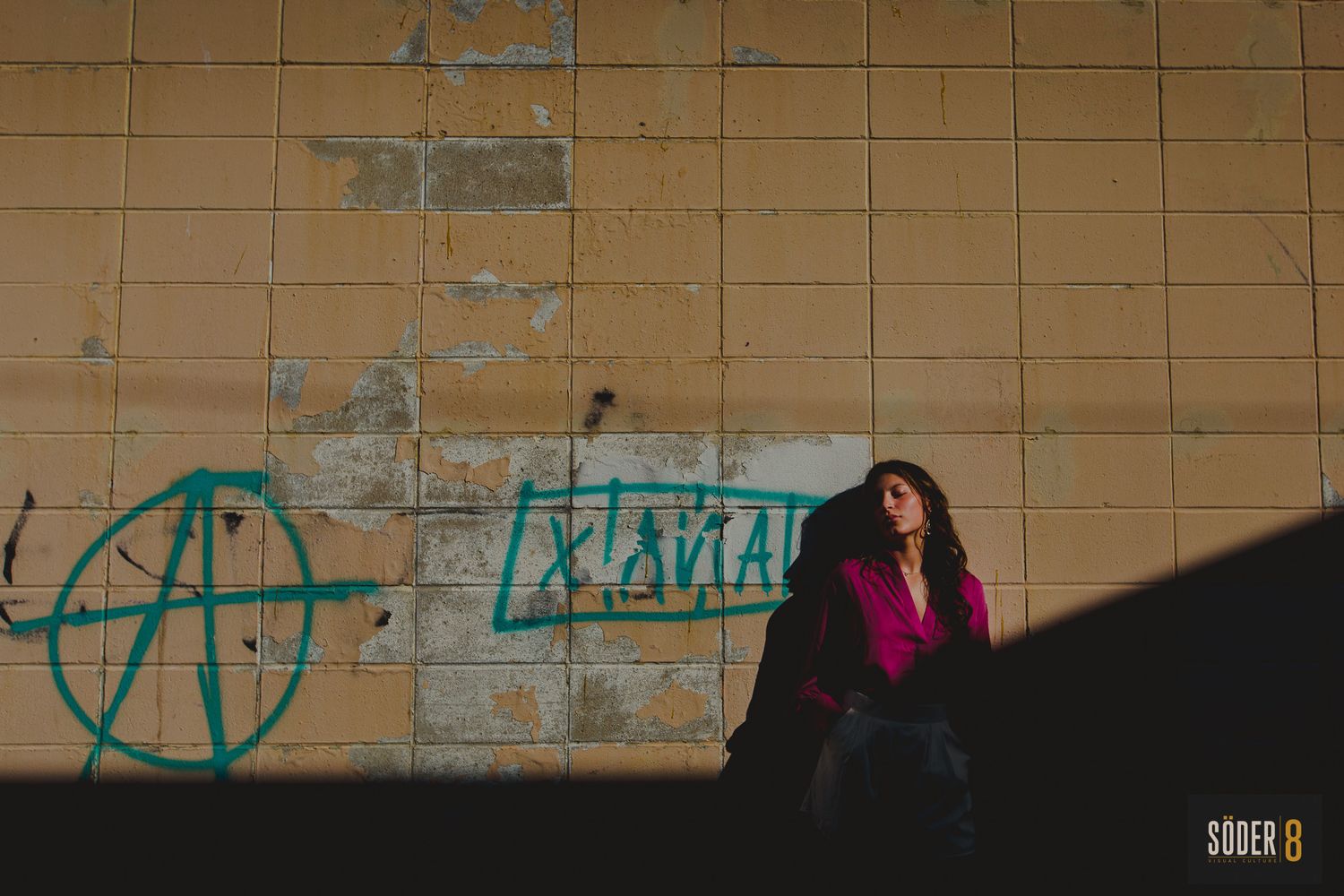 high school senior in clear lake, iowa standing next to a wall in light and shadows with graffiti - soder 8