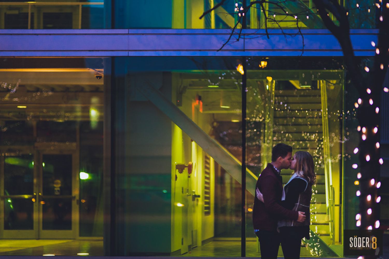 engagement session in downtown davenport iowa man and woman hugging at night in front of lit up store window