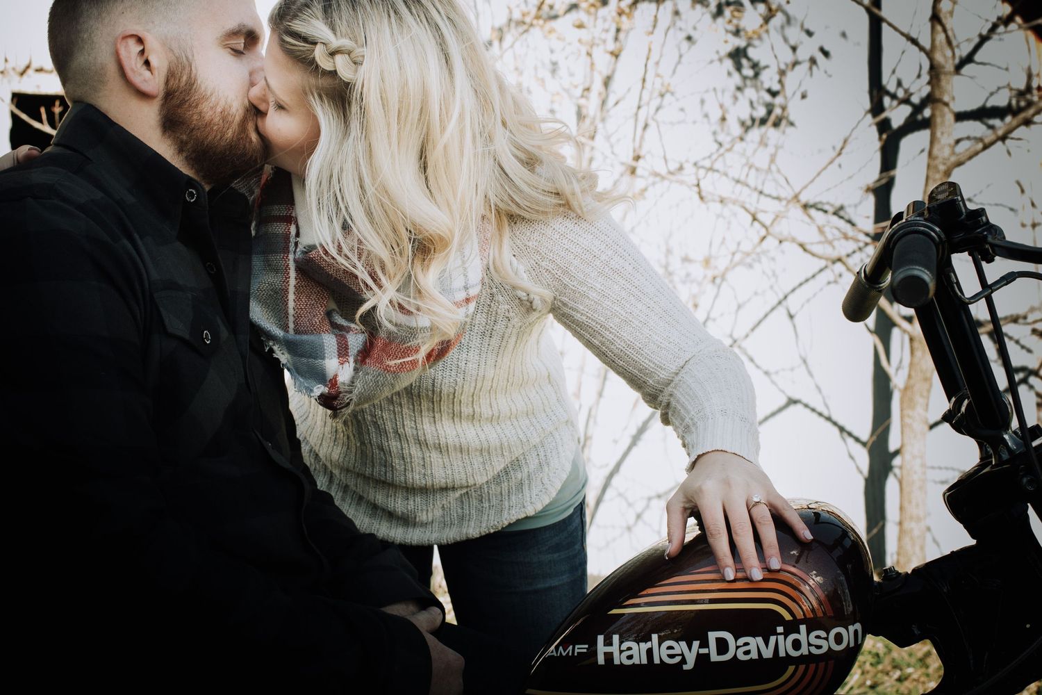 man on Harley and woman leaning in and kissing him during iowa engagement session