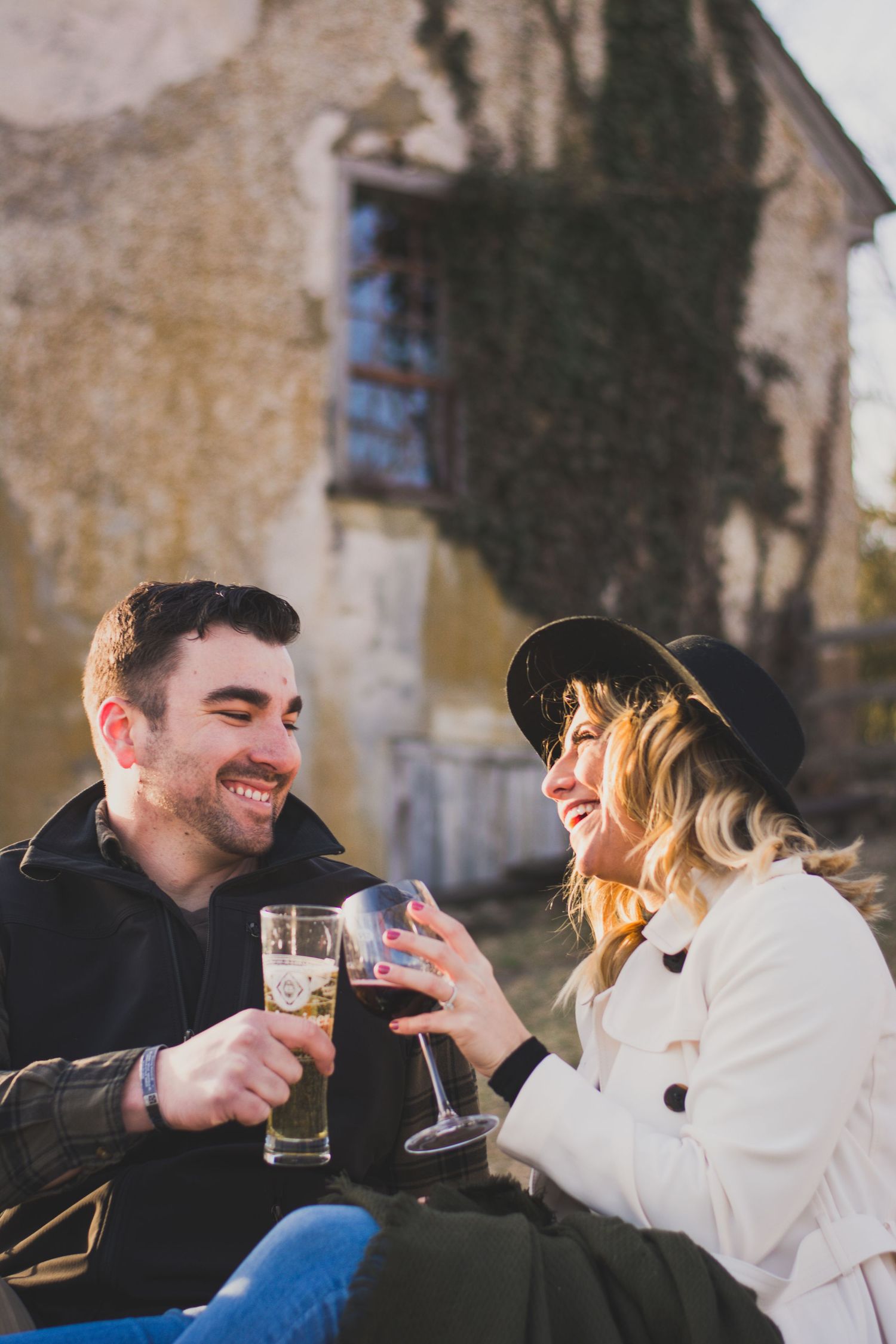 Smiling couple toasting with glasses of champagne outdoors near a vintage stone building.