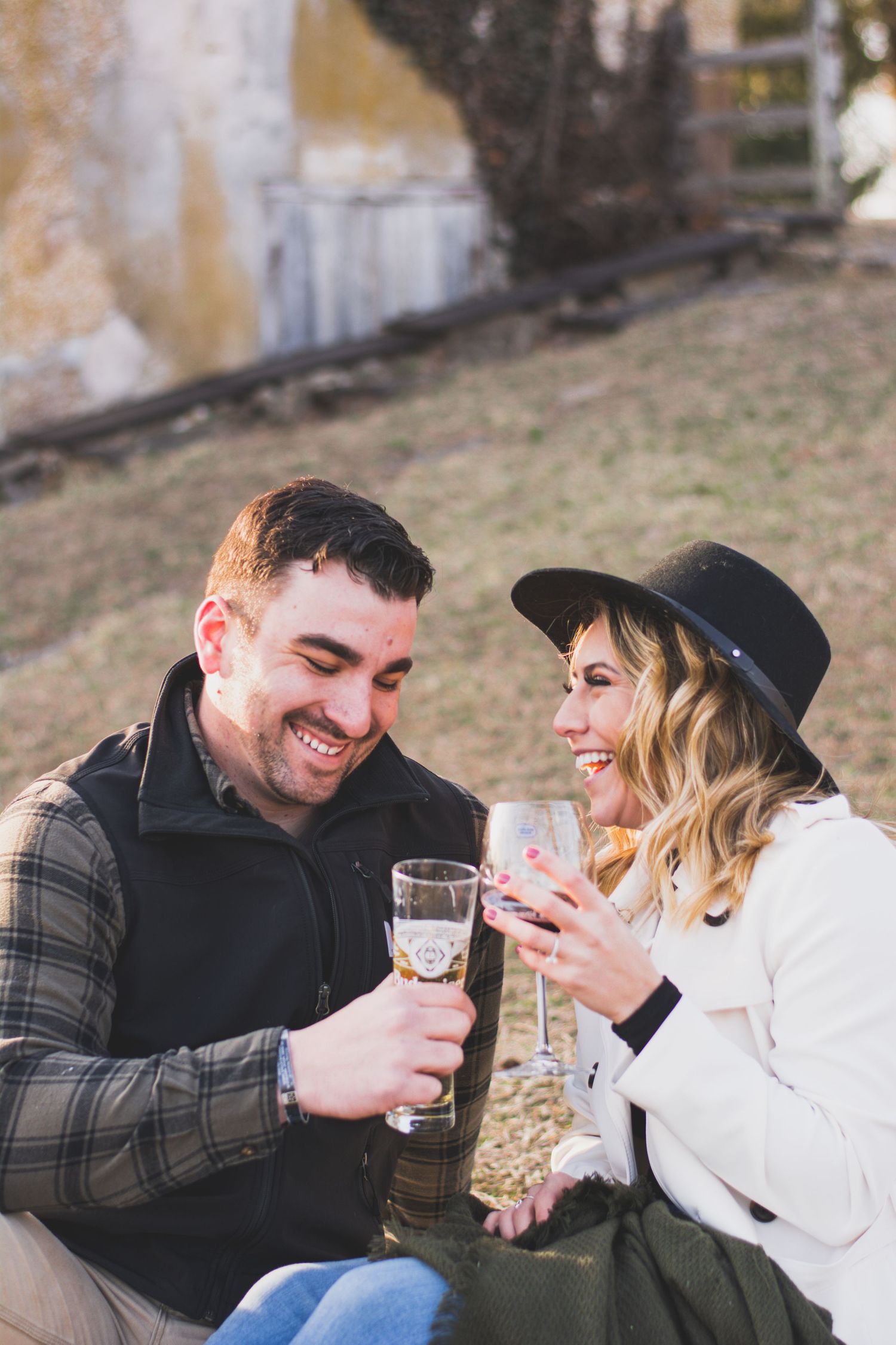 Happy couple laughing and toasting with champagne glasses outdoors in autumn setting.