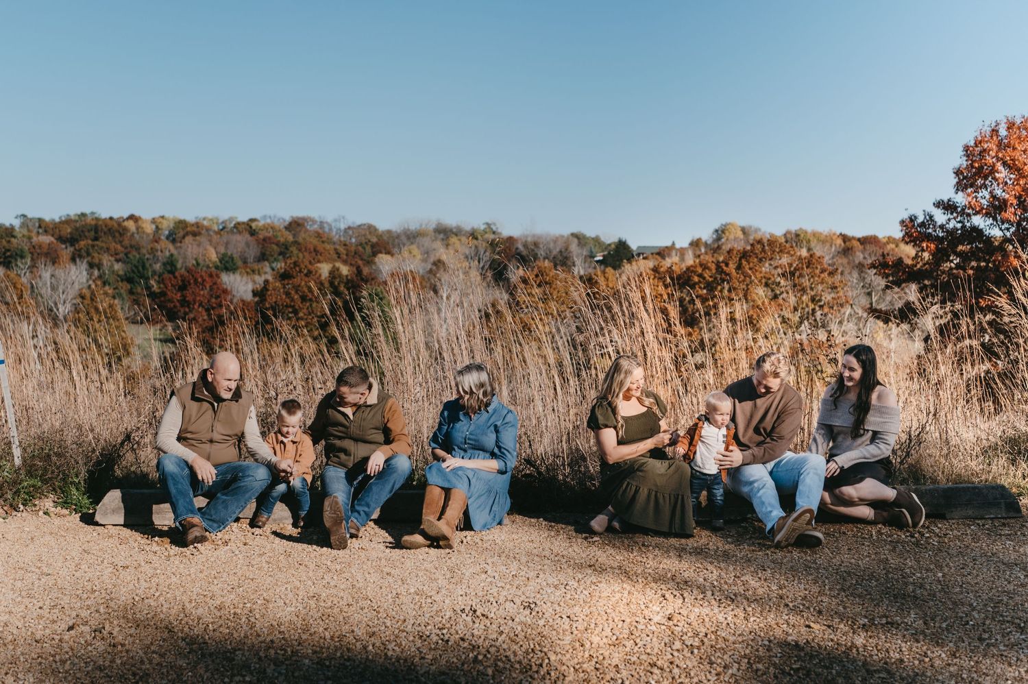Extended family sitting together on a dirt path surrounded by autumn tall grass fields. Hudson, Wisconsin.