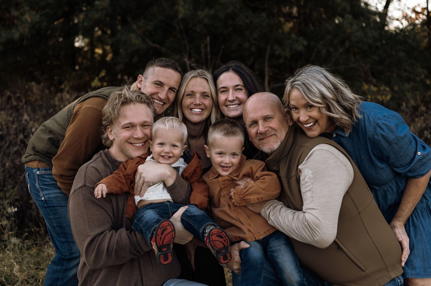 Large family group hugging and smiling together outdoors during fall season photo session. Hudson, Wisconsin.