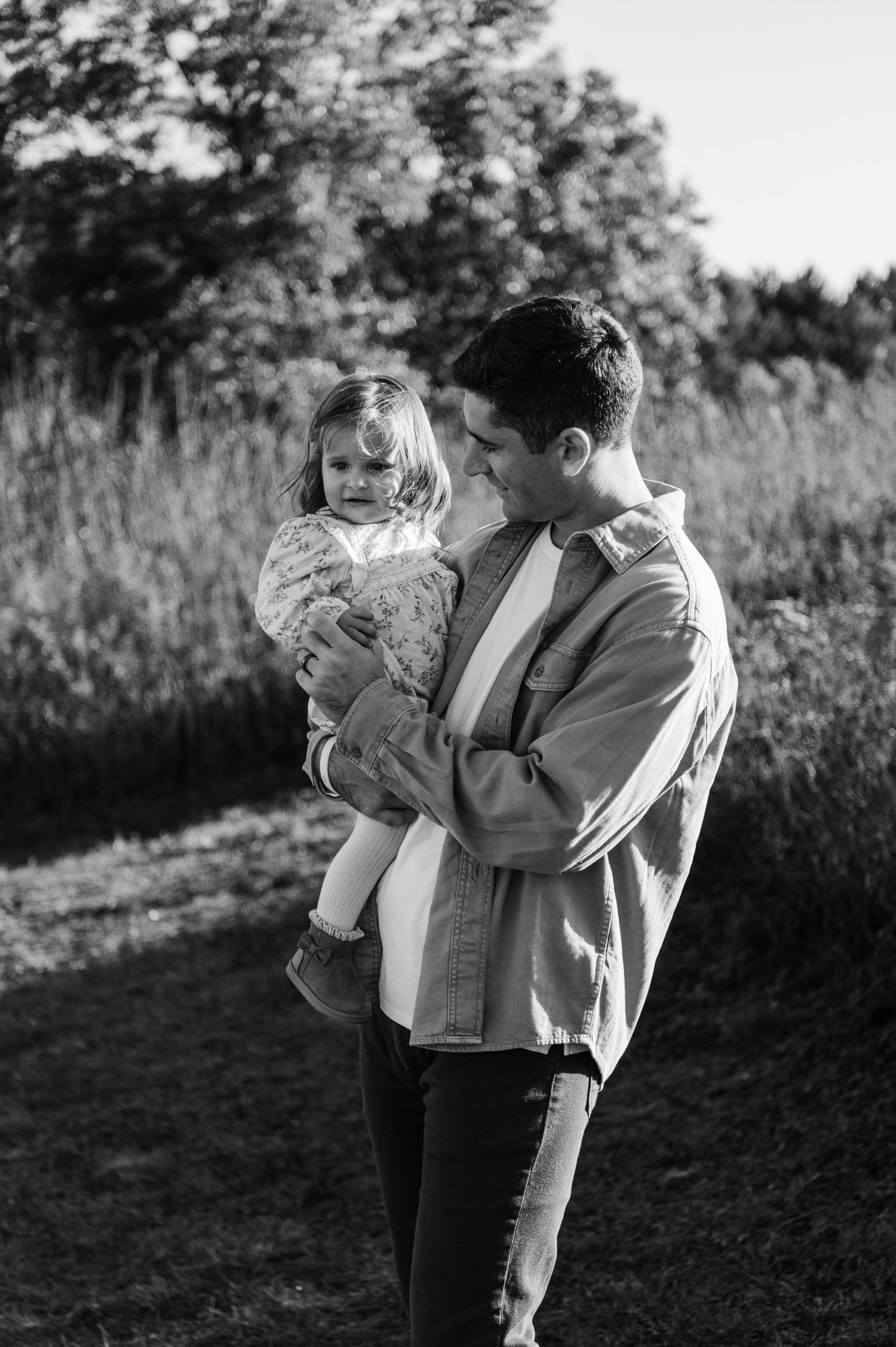 Black and white photo of a father tenderly holding his young toddler daughter outside. Hudson, Wisconsin.