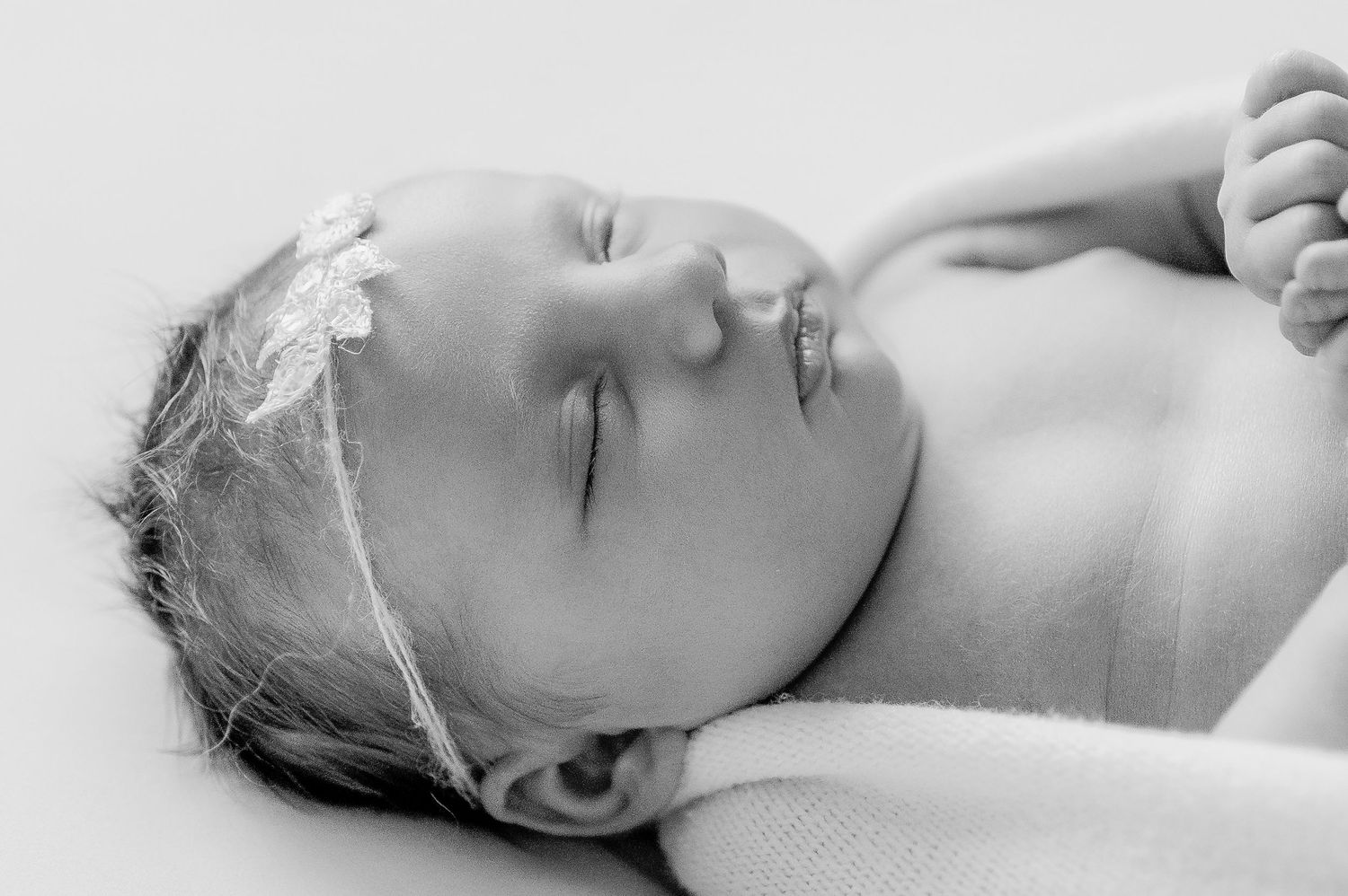 Peaceful sleeping newborn baby girl wearing a delicate floral headband in black and white. newborn photography. Wisconsin. Minnesota.