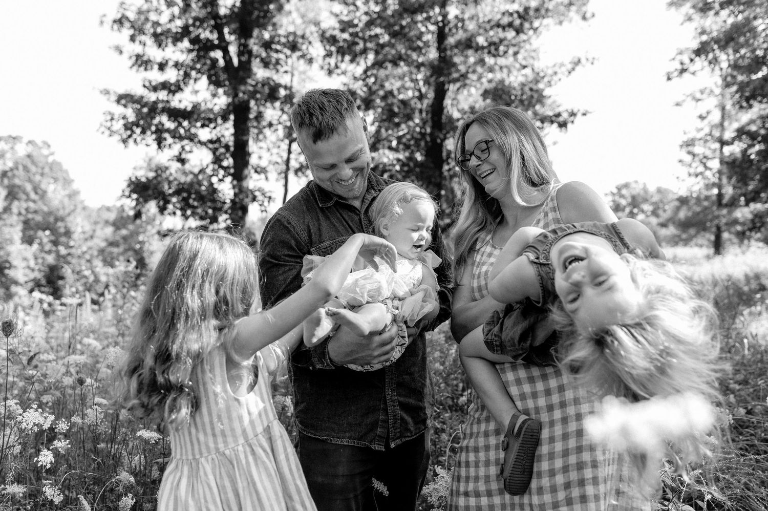 A family of five gathers in a wildflower field in a black and white photo.