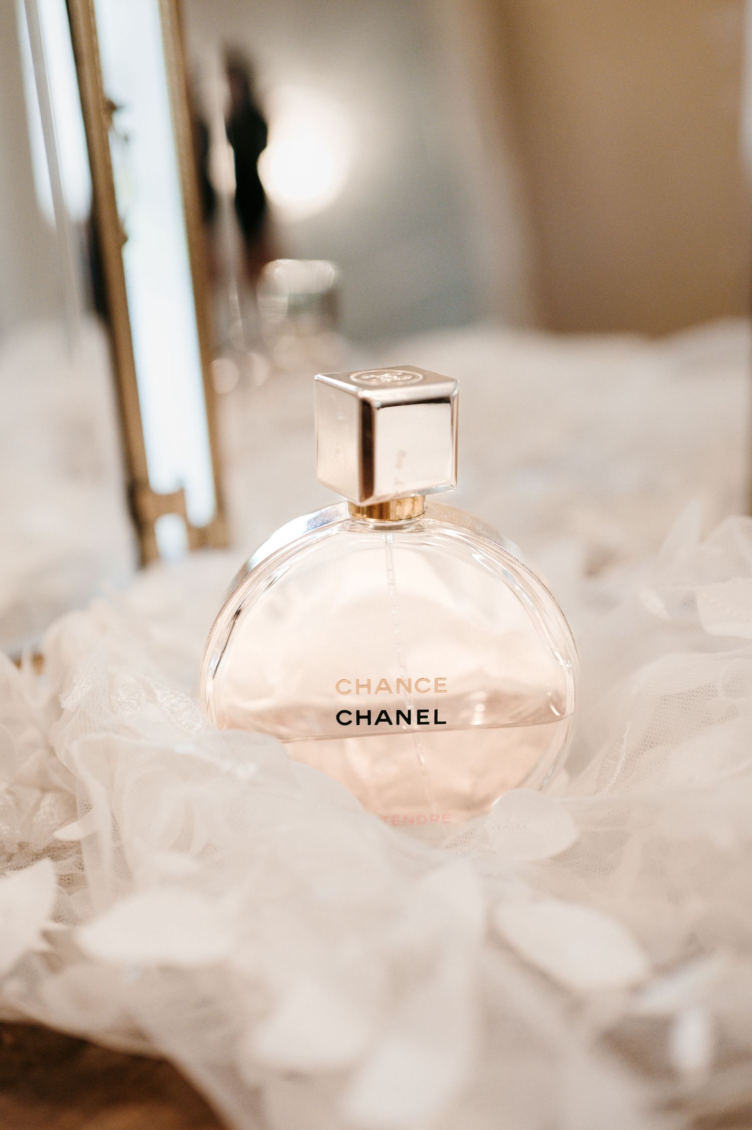 Chanel Chance perfume bottle resting on white tulle fabric for wedding flat lay.