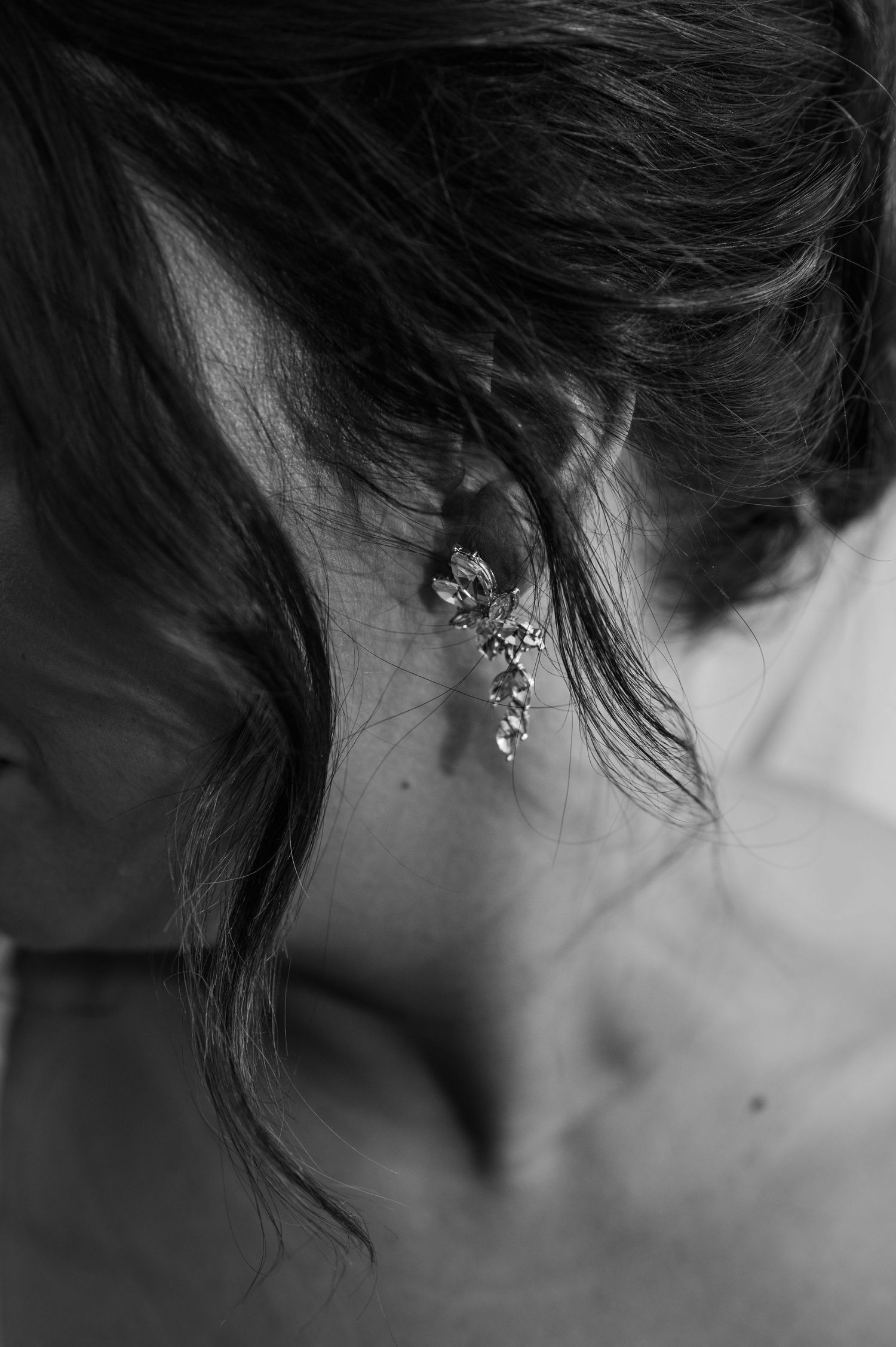 Black and white close-up of bride wearing elegant chandelier earring on wedding day.