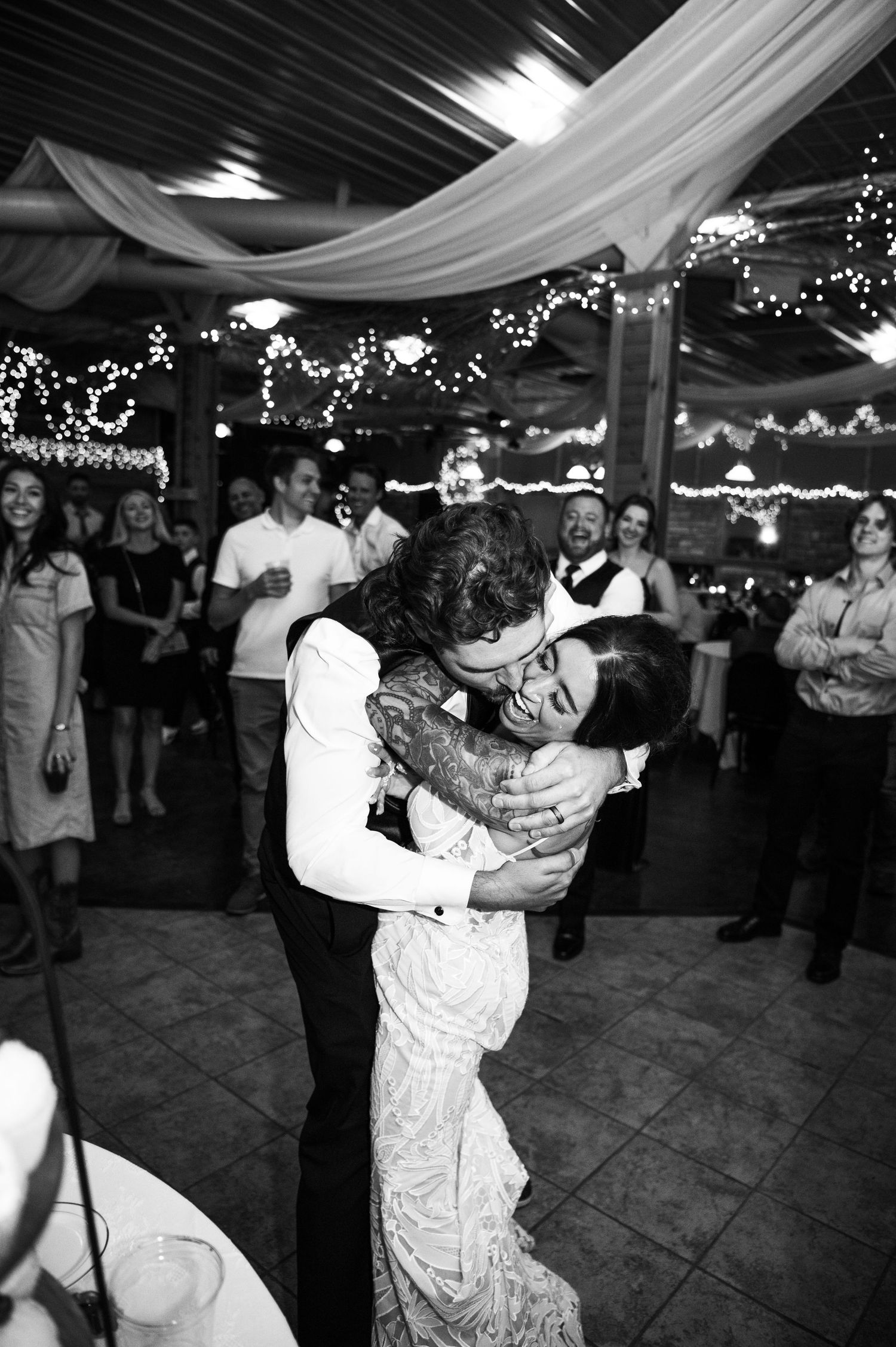 Black and white photo of bride and groom sharing first dance at wedding reception.