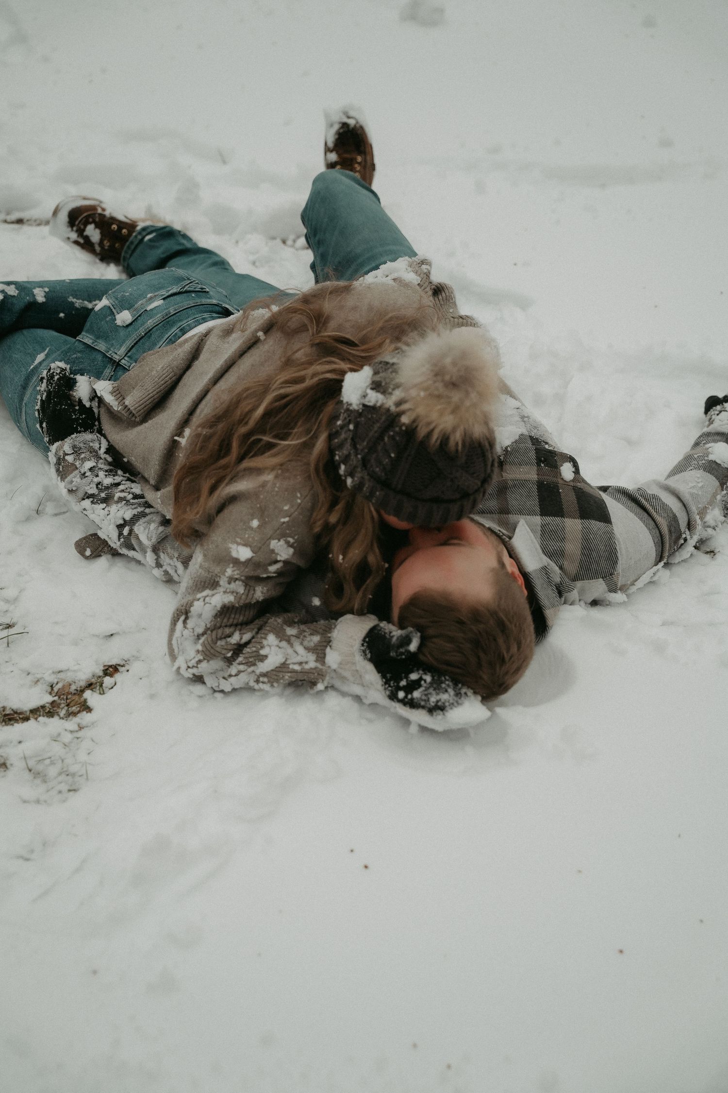 Multiple shots of someone making snow angels in the snow while wearing winter outerwear and boots.