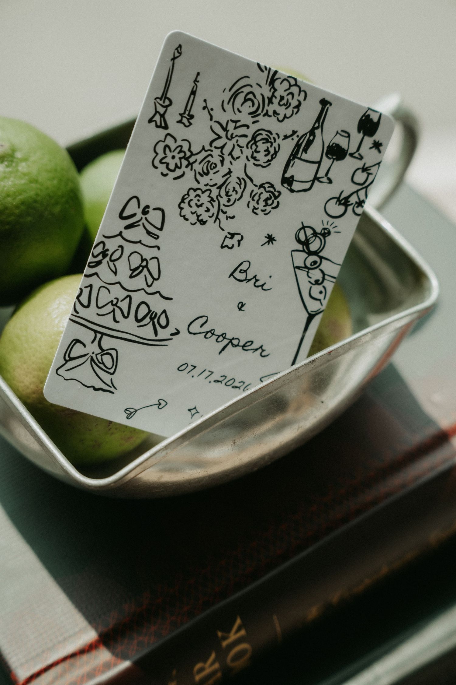 Custom illustrated wedding card for Bri and Cooper dated 07.17.2020, leaning against limes in a silver bowl.