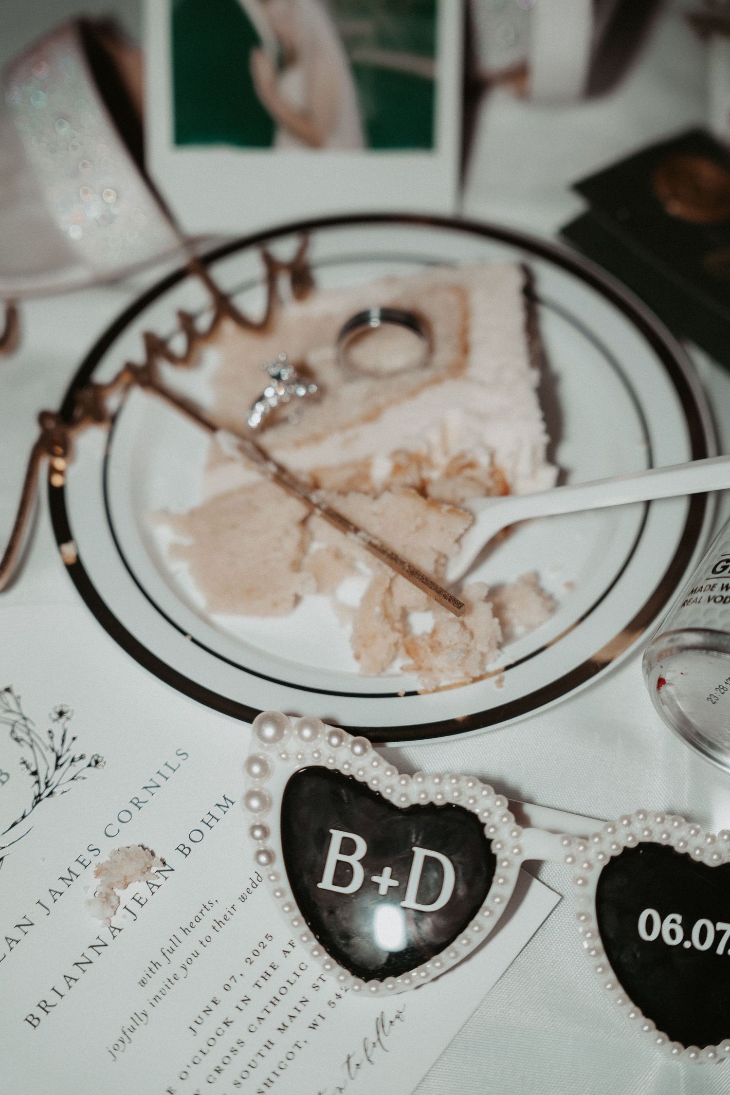 Wedding details with a heart-shaped decor displaying B+D and a date on an invitation with leftover cake crumbs.