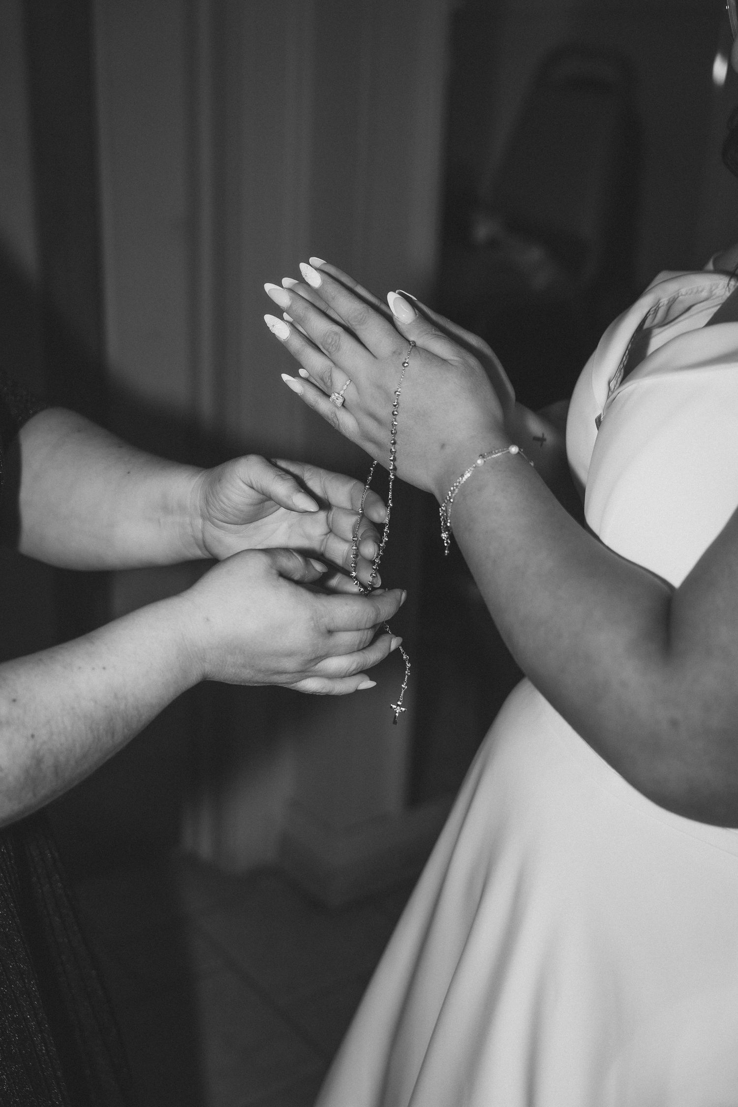 A series of black and white photos showing hands helping to button up the back of a white wedding dress.
