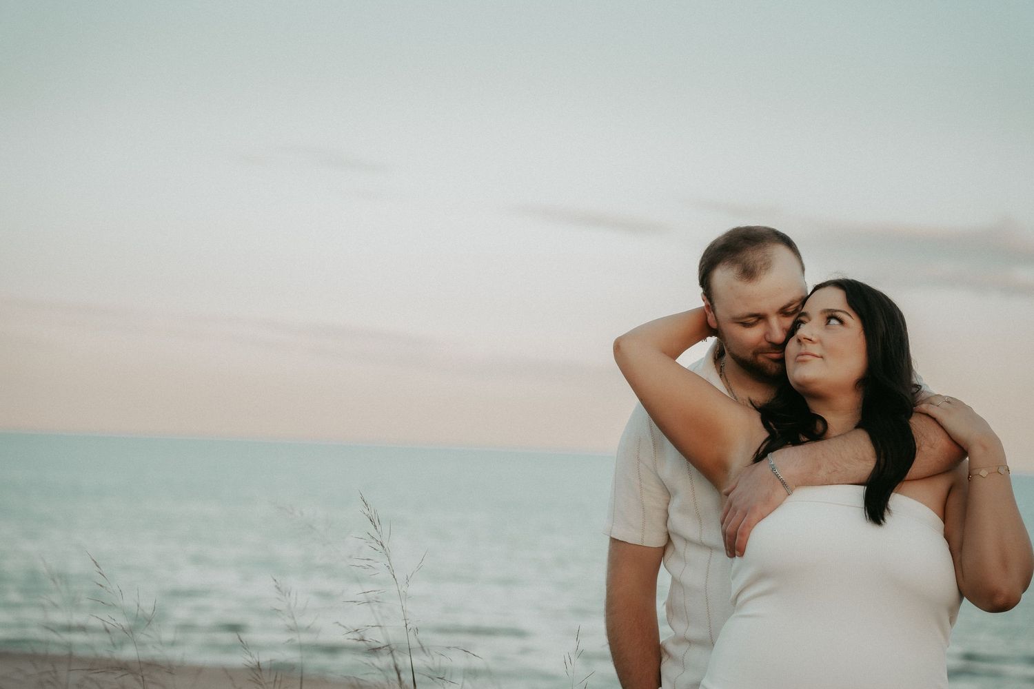 A romantic beach photoshoot sequence showing tender moments between a couple against an ocean backdrop.