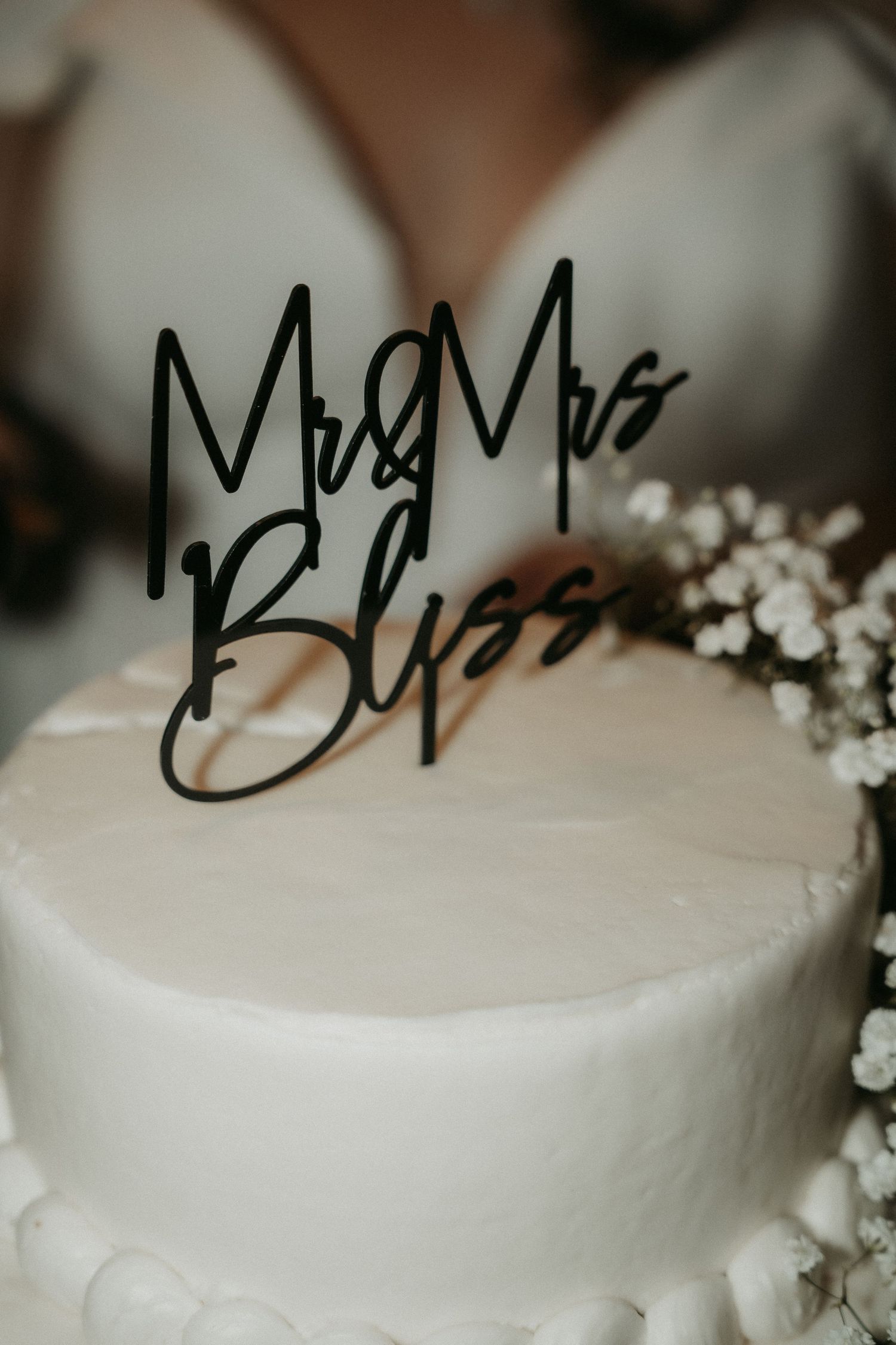 A close-up view of a simple white wedding cake decorated with delicate baby's breath flowers.