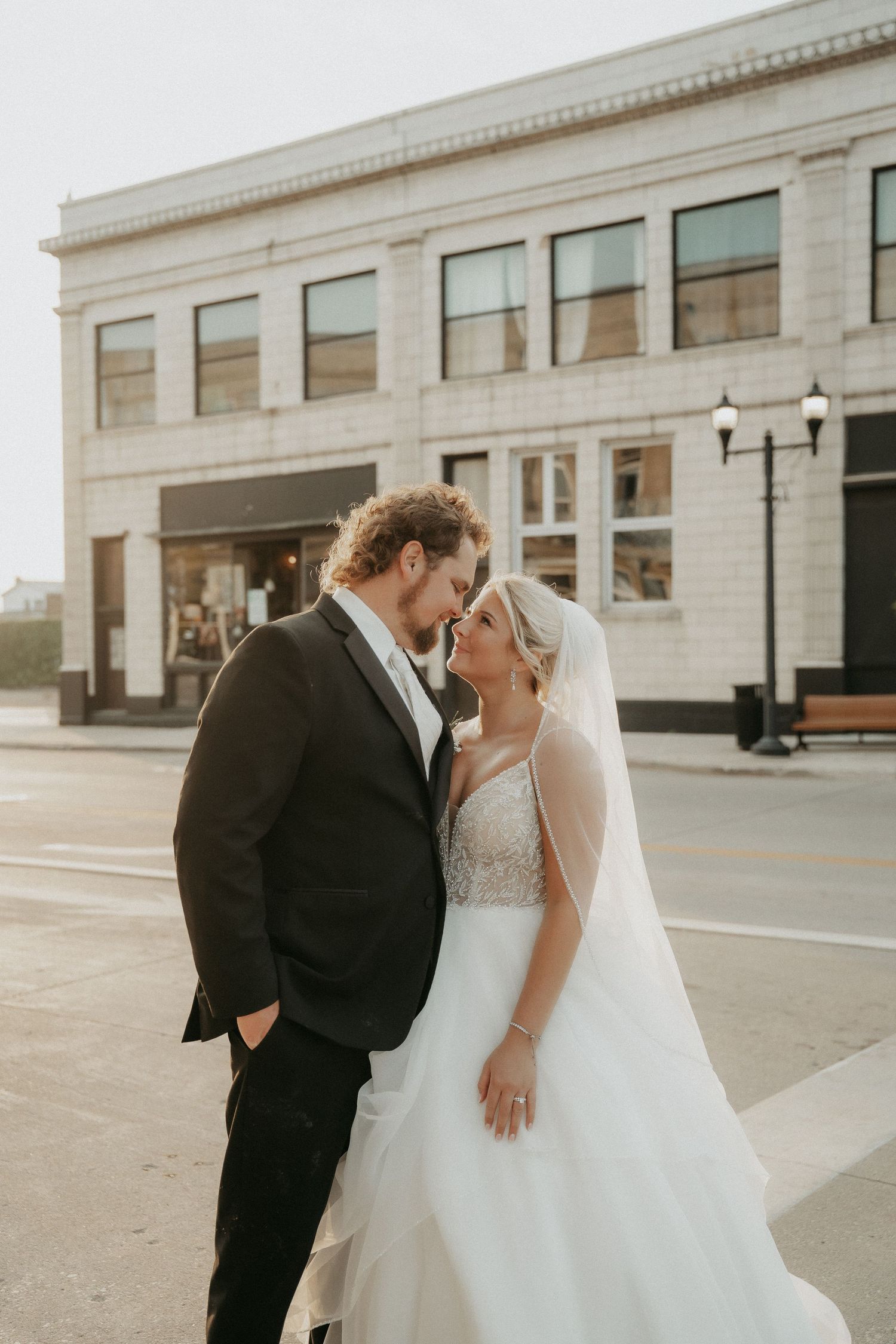 A romantic wedding couple shares intimate moments in front of an industrial building exterior.