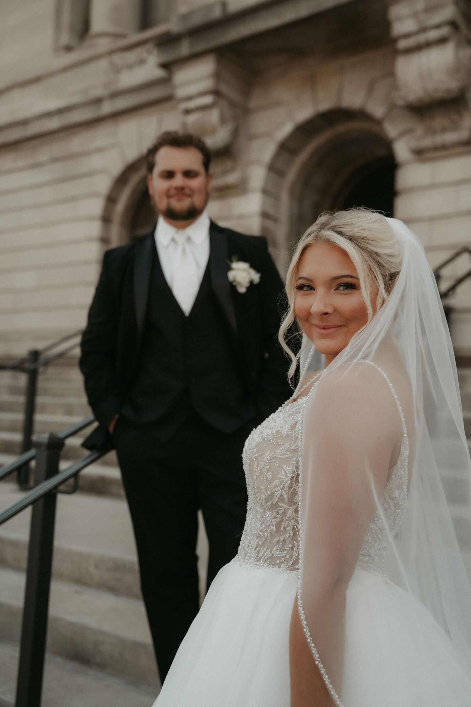 A romantic wedding photo series showing the couple in formal attire outside a grand stone building.