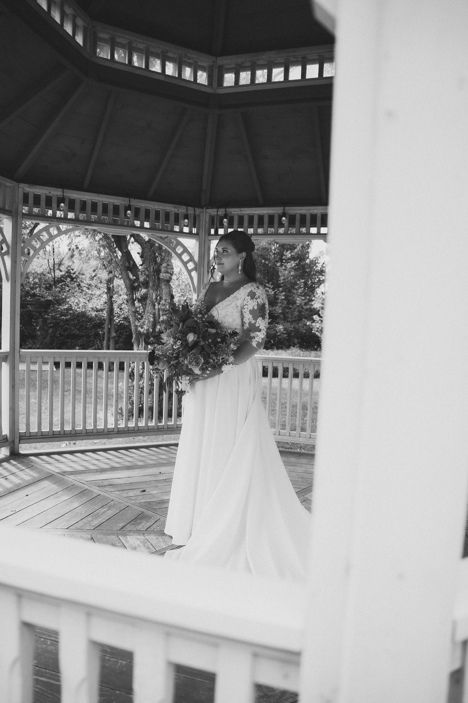 White wooden gazebo with decorative trim and railings creates an elegant architectural focal point in an outdoor setting.