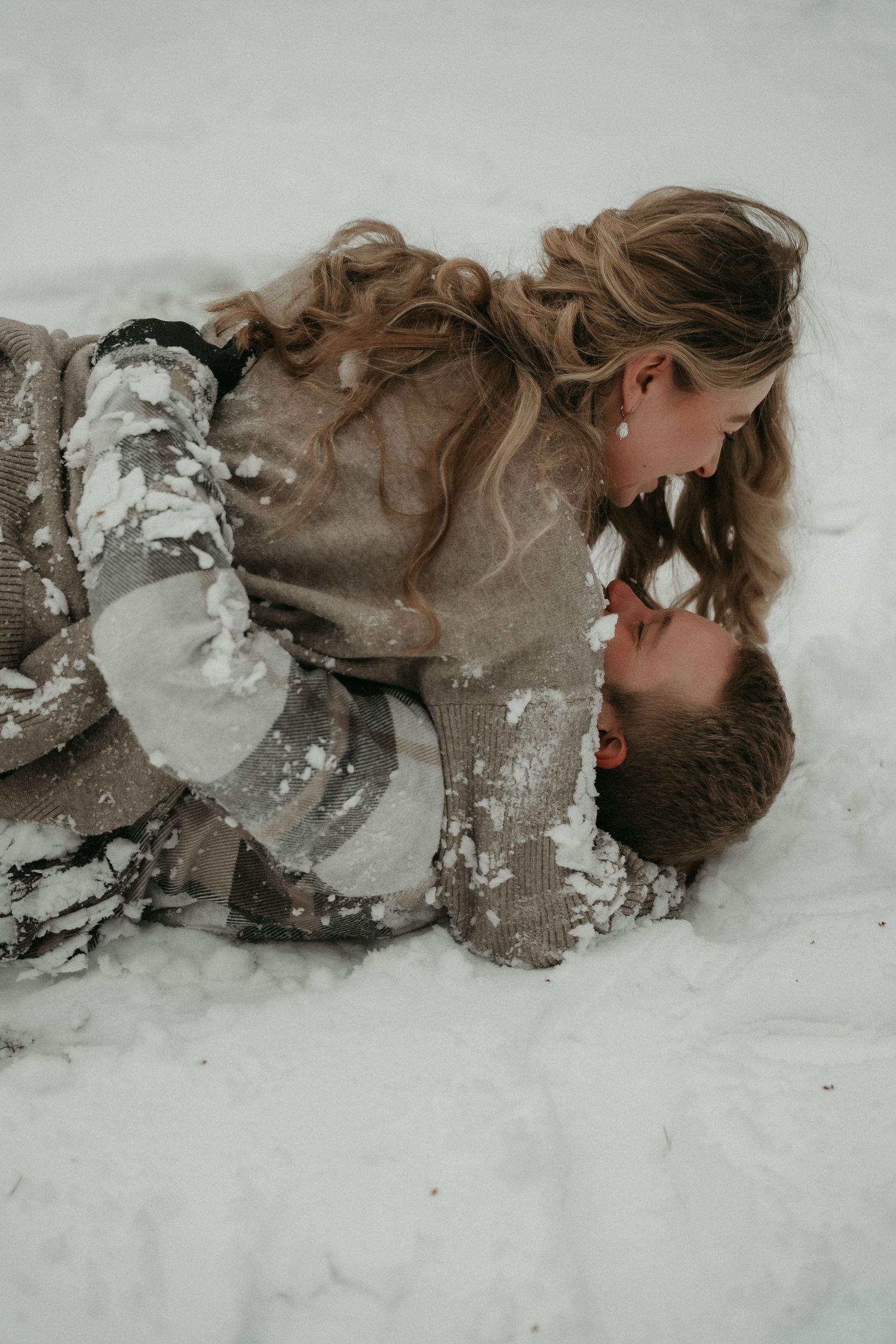 A series of artistic photographs showing a person lying in snow with abstract white and gray textures creating a dreamlike effect.