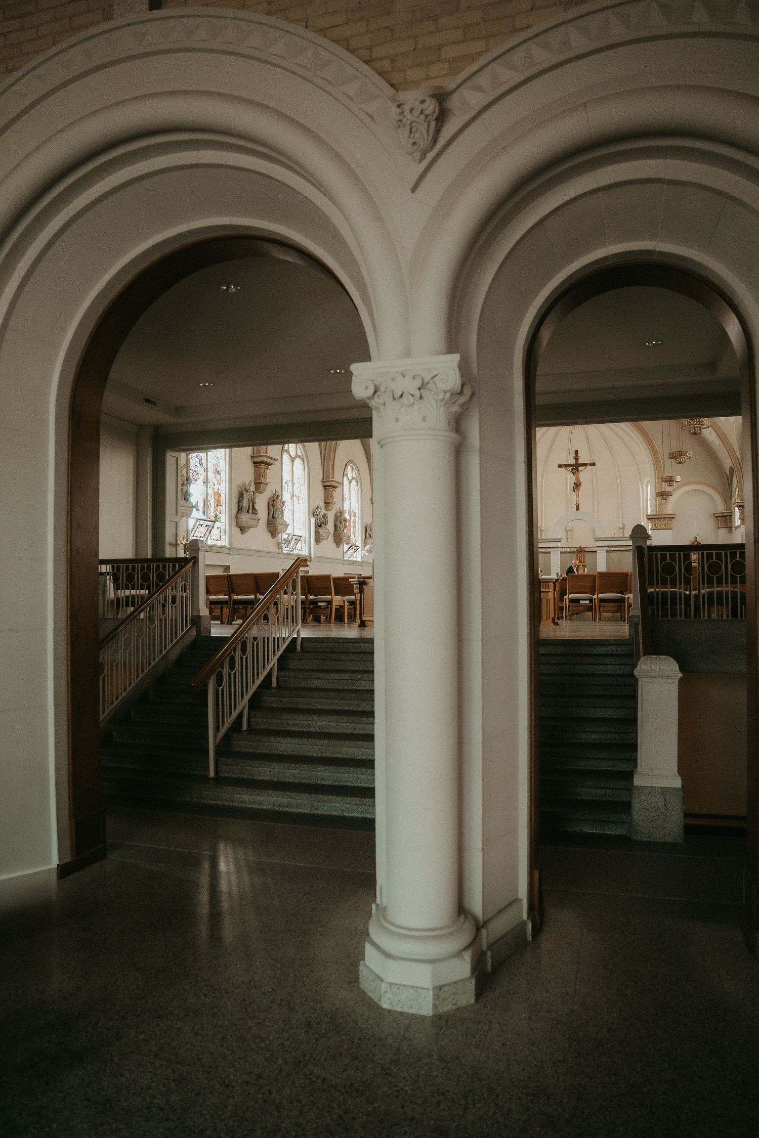 Interior arches and columns frame the dark wooden pews in a historic church sanctuary with moody lighting.