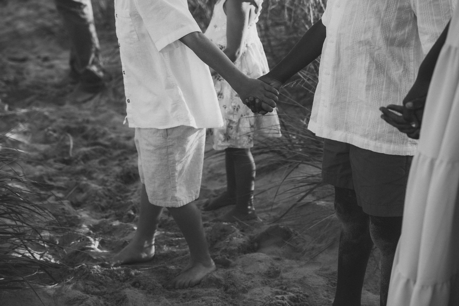 A couple stands together in shallow ocean water during a beach wedding ceremony.