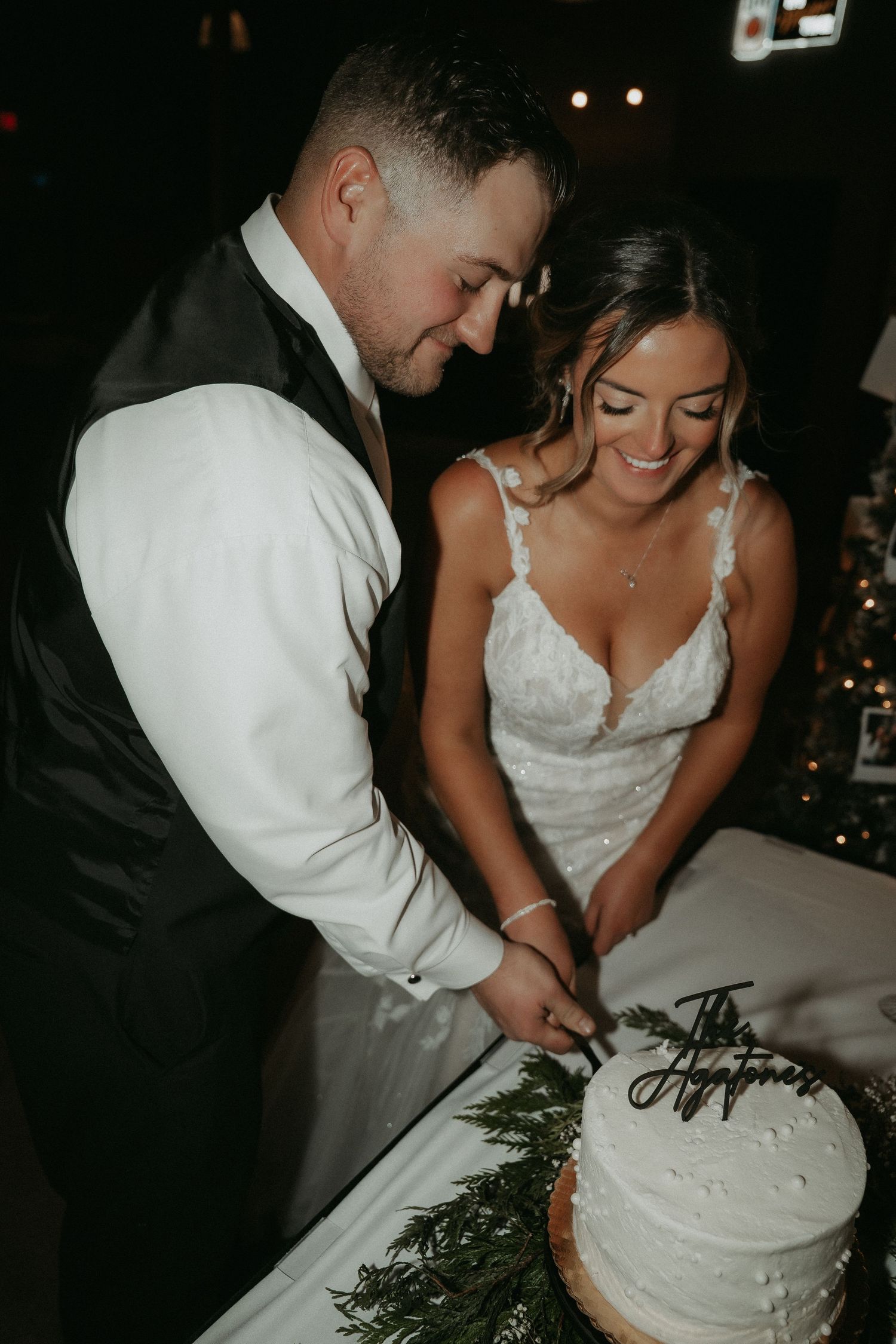 Newlyweds cut their wedding cake together in a dimly lit reception venue, captured in a sequence of candid moments.
