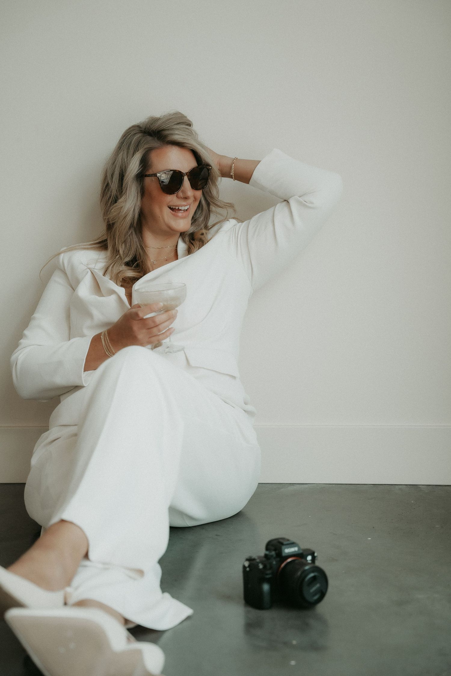 Fashion model in white oversized shirt poses on concrete floor in artistic minimalist photo series.