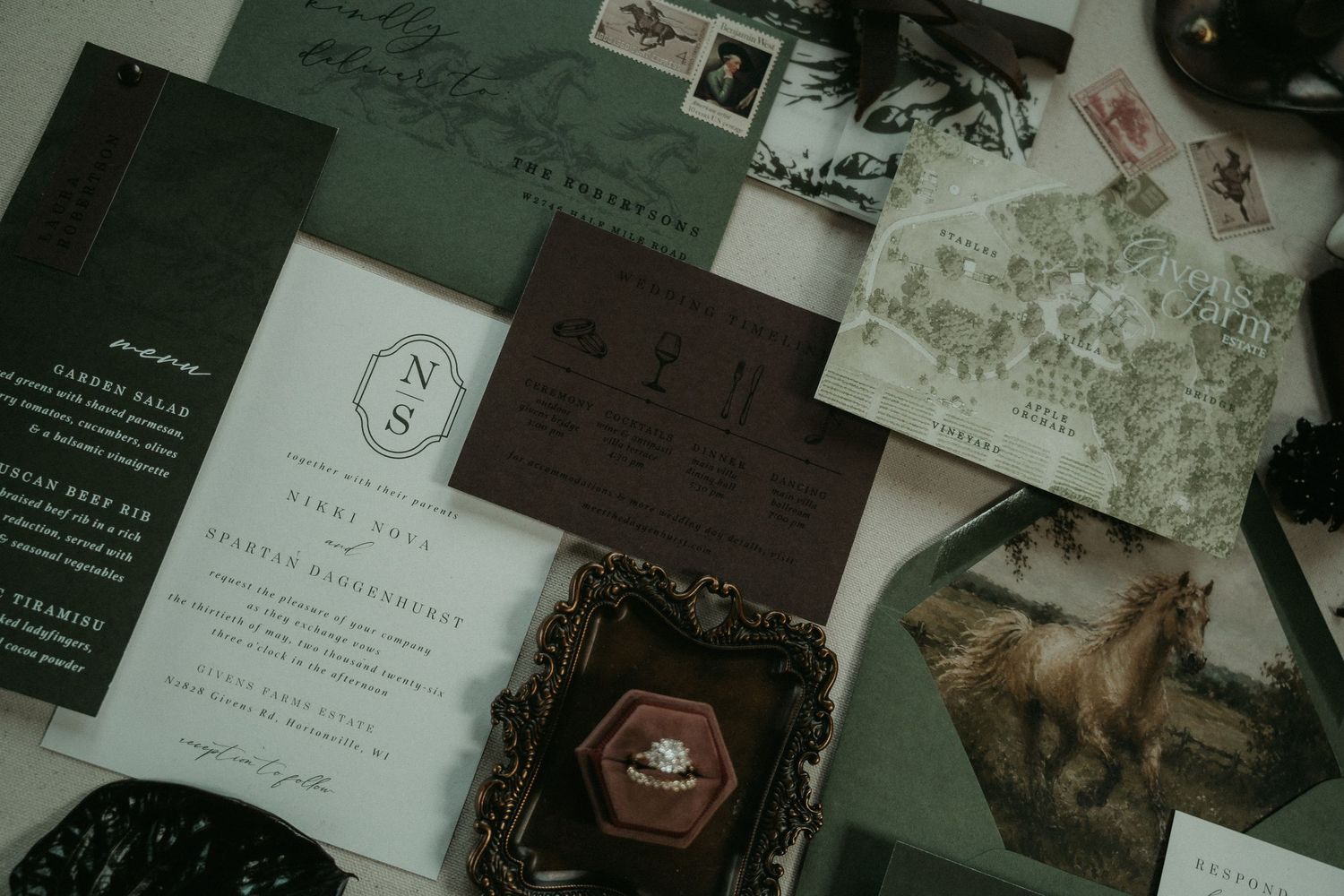 Elegant dark green wedding stationery suite with monogram cards, map details, ring box, and vintage-style invitations flatlay.