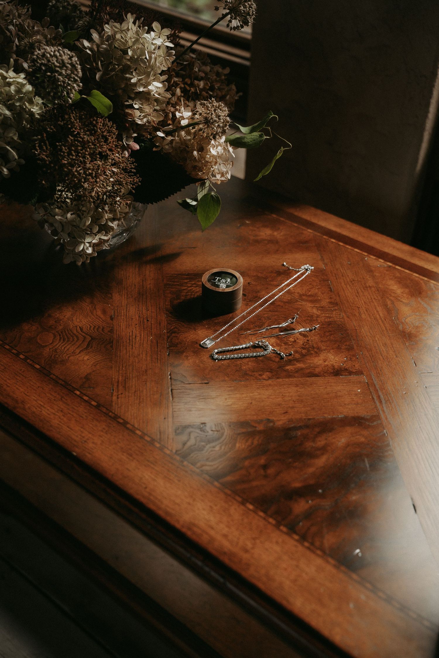 Silver scissors rest on a rustic wooden table surface with soft lighting and shadows.