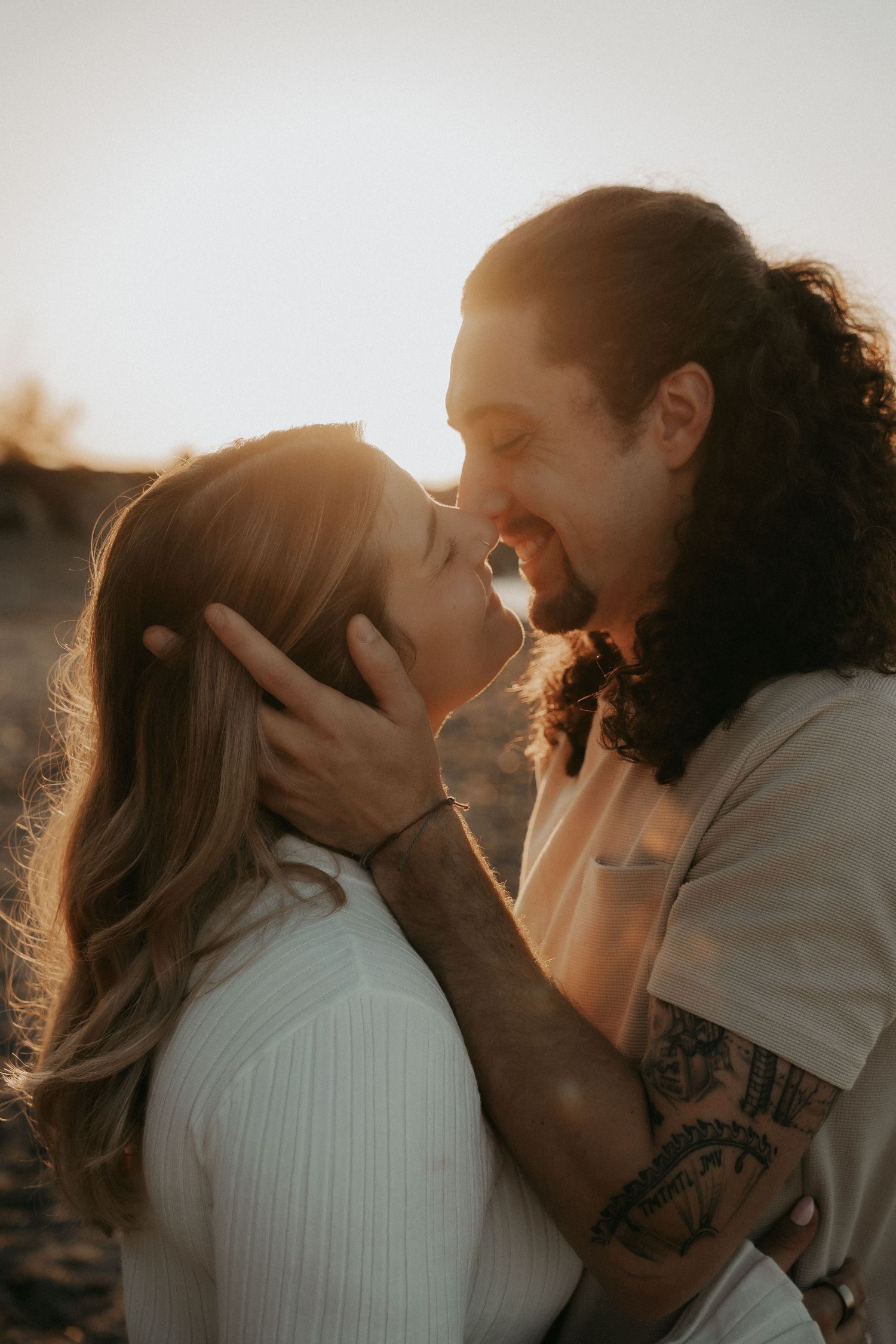 Romantic couple embraces and kisses during golden hour sunset in a series of intimate candid photos.