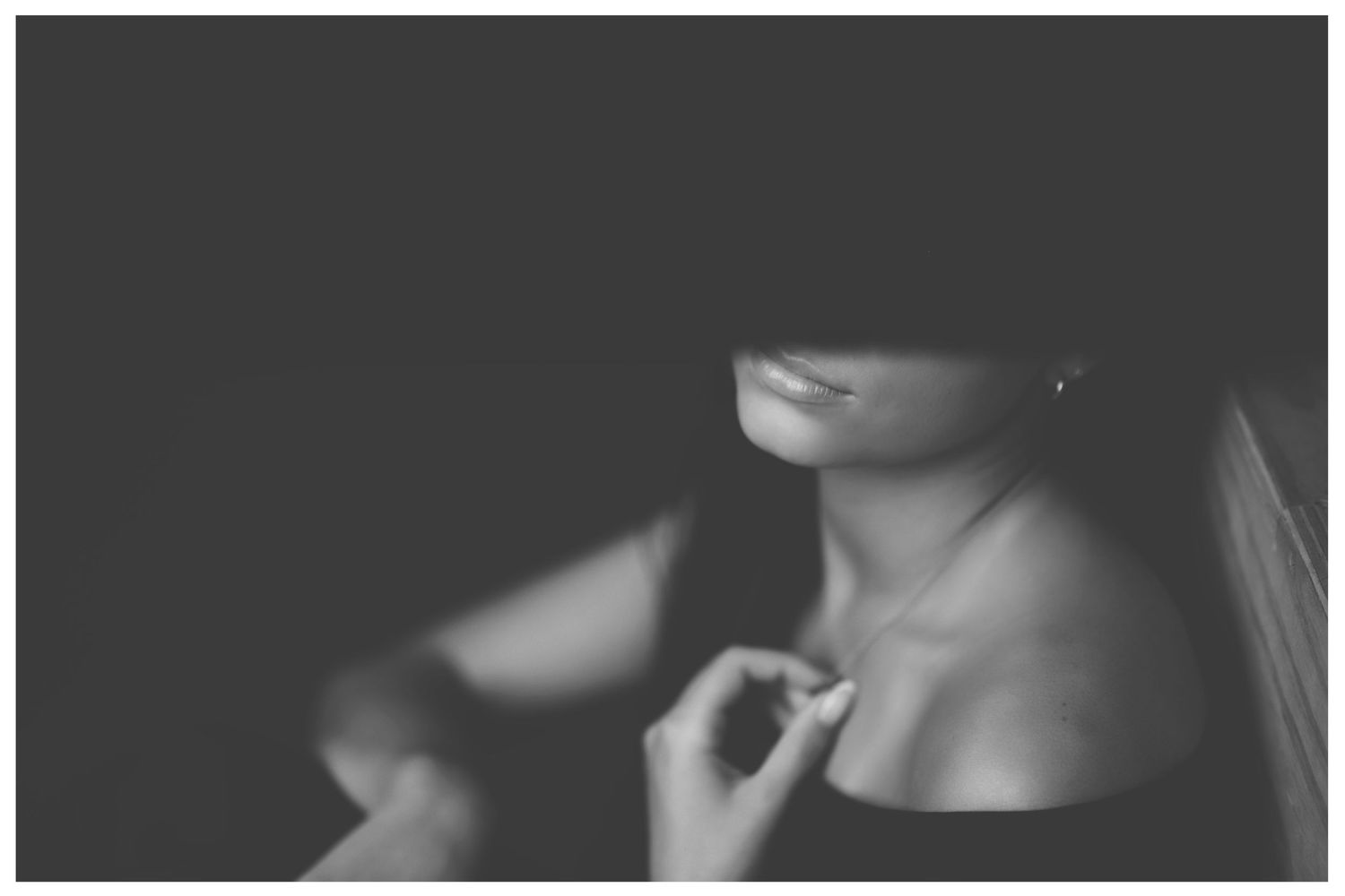 Dramatic black and white close-up portrait showing bare shoulders and neck in moody lighting.