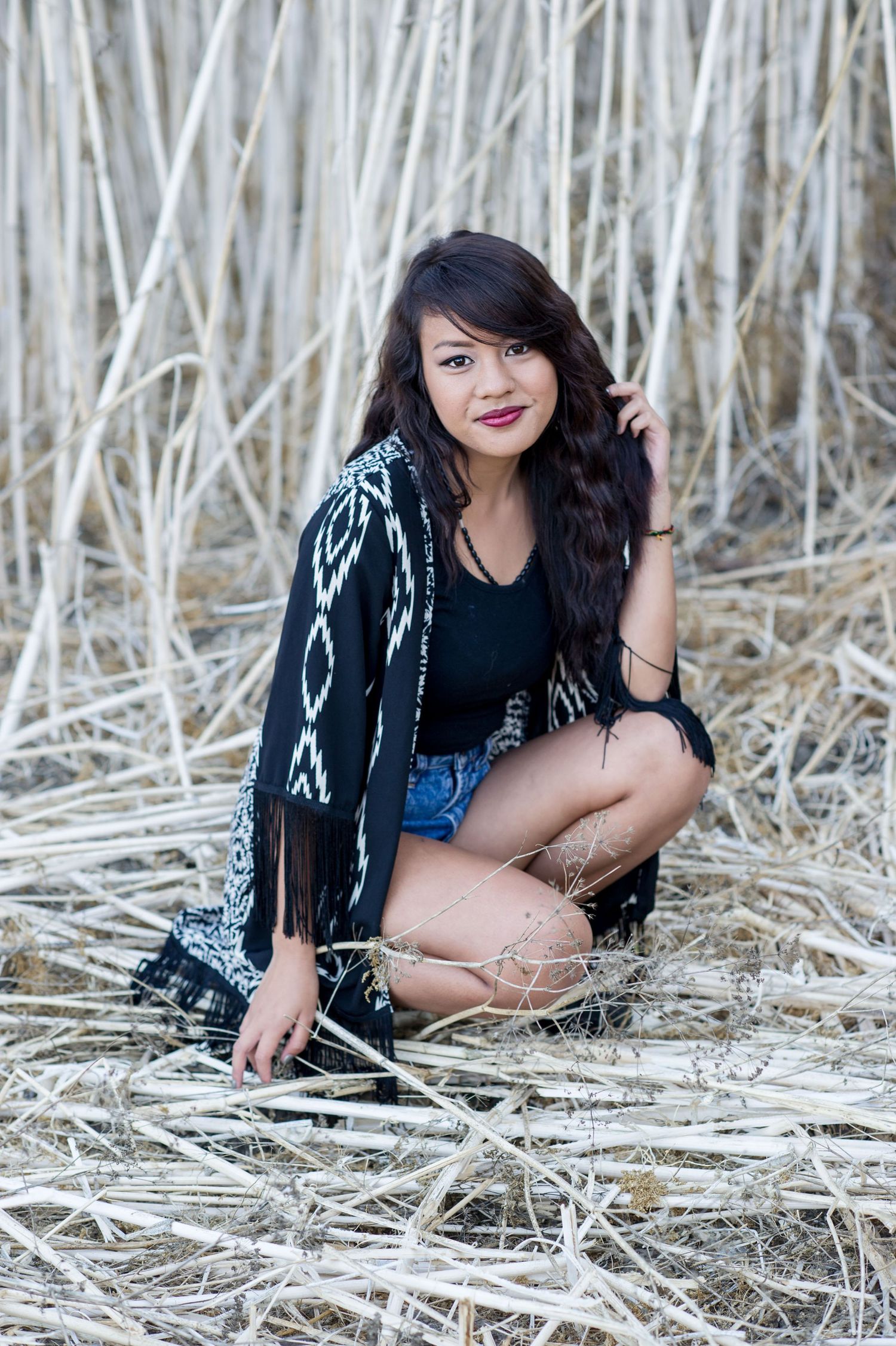 Fashion portrait in a field of dried reeds featuring a patterned cardigan and denim shorts.