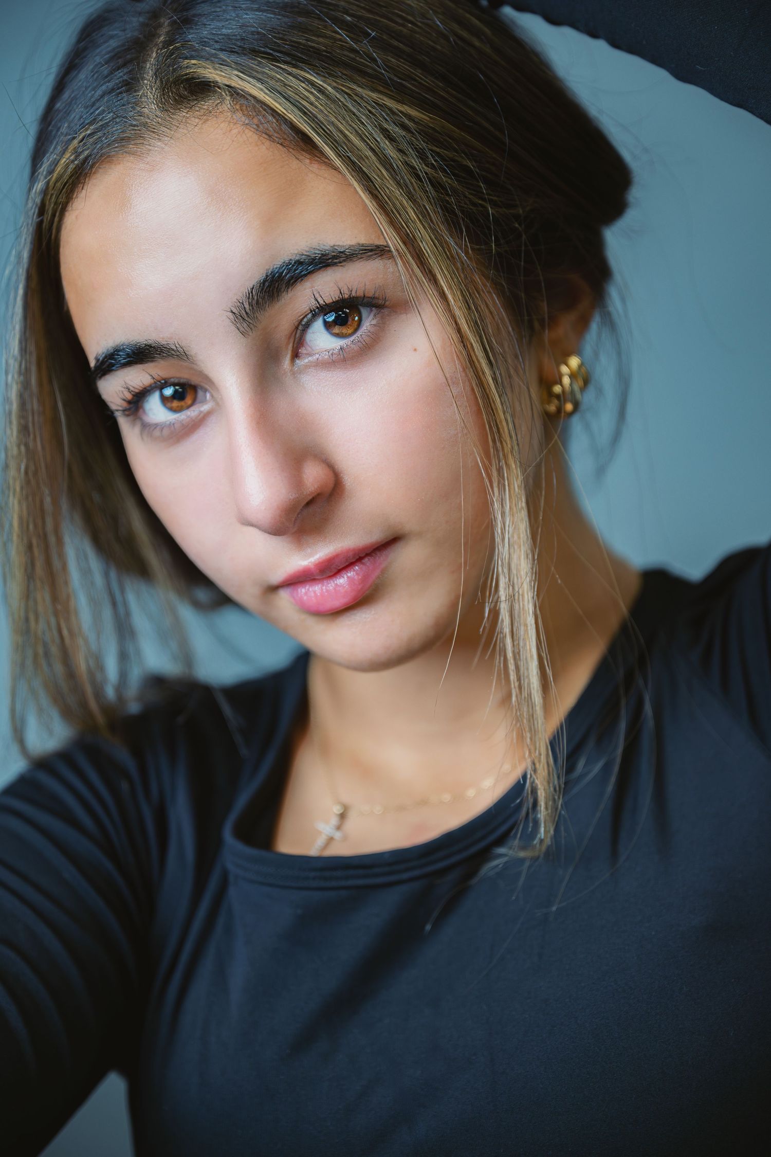 A series of selfie portraits showing someone in a black top against a dark background with moody lighting.