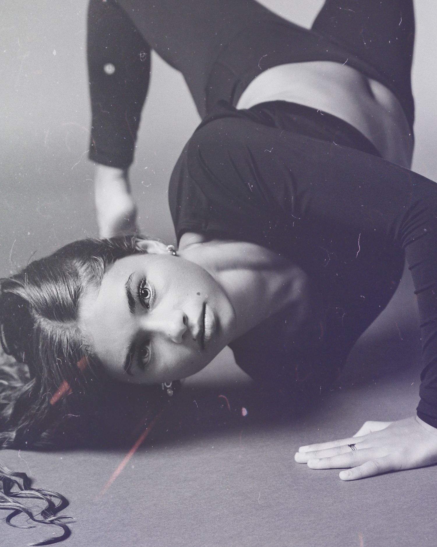 A black and white artistic photo series showing a person lying on the floor in dramatic poses.